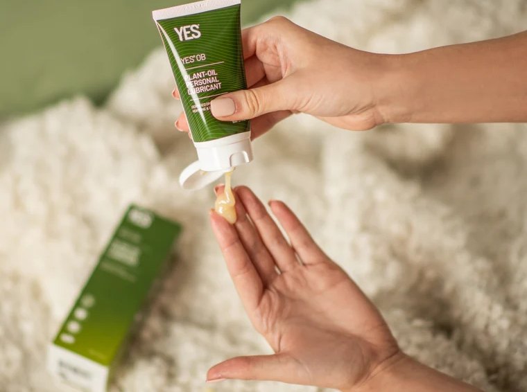 Hands dispense YES OB plant-oil lubricant from a green tube