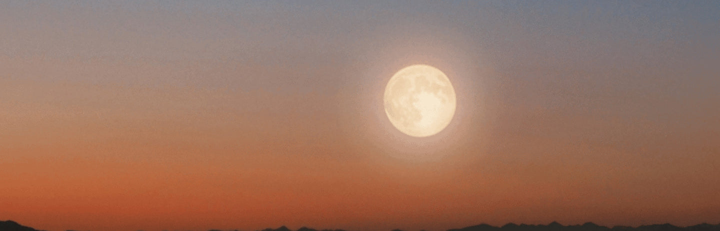 A bright moon over hills at dusk